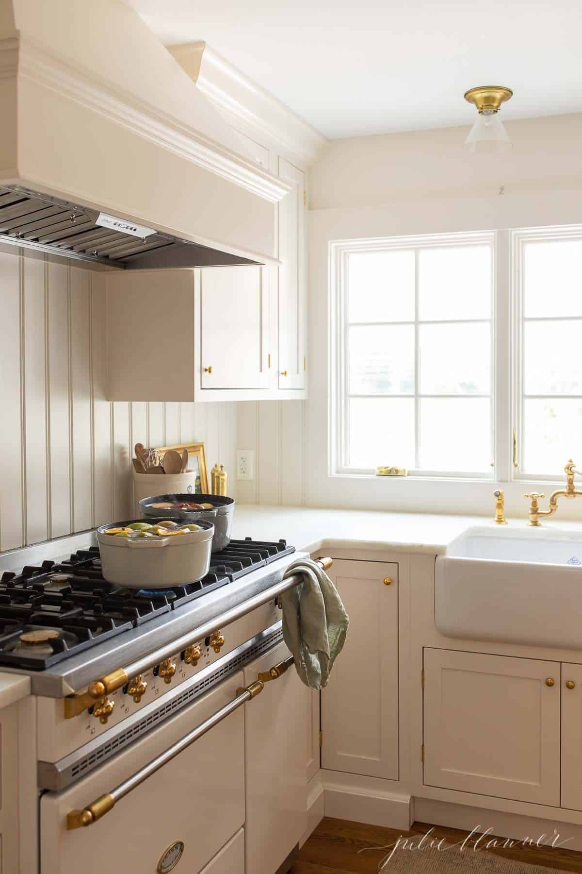 A white kitchen with two pots simmering on the stove.