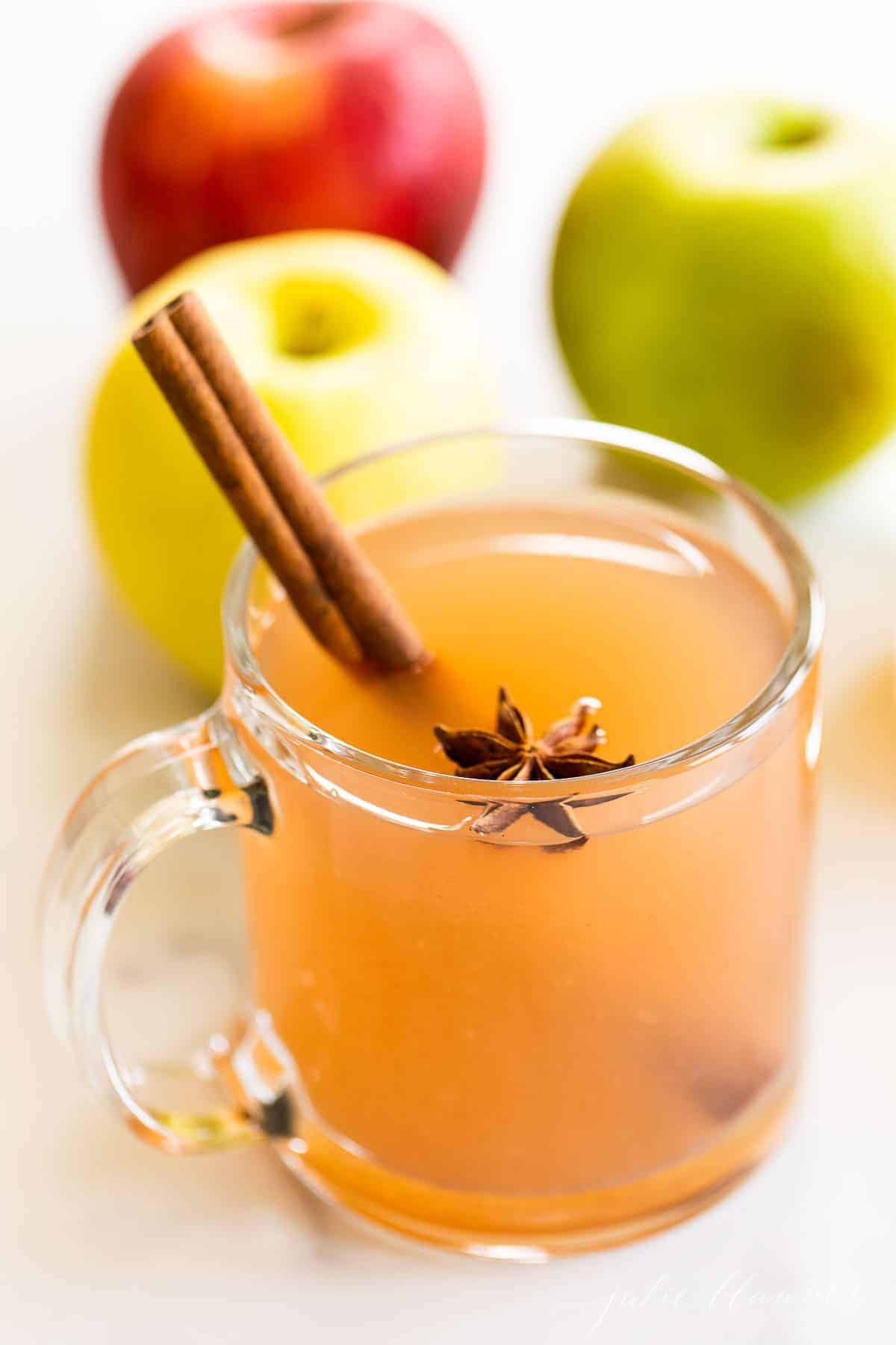 A clear glass mug full of warm apple cider for a virtual thanksgiving celebration.