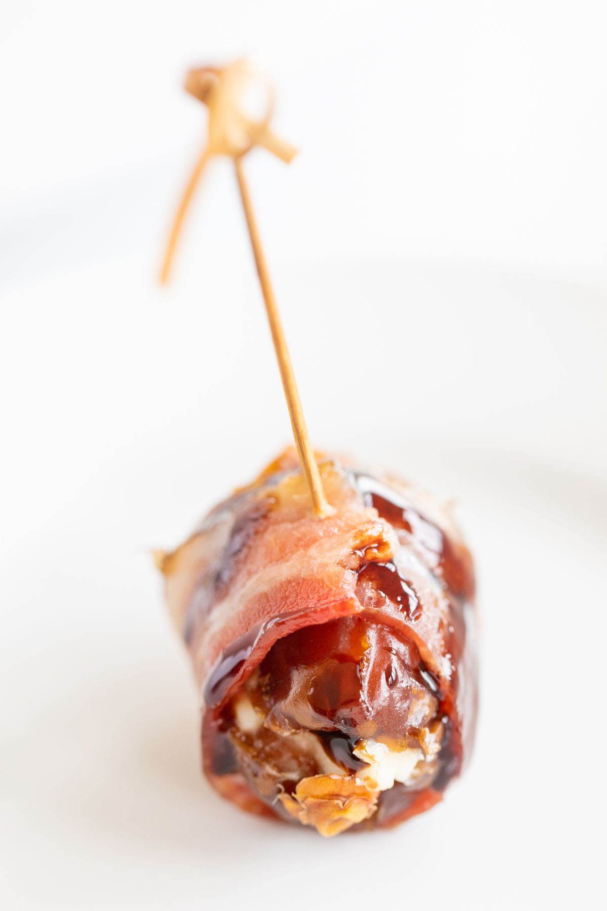 A close up of stuffed dates wrapped in bacon and drizzled in balsamic glaze.