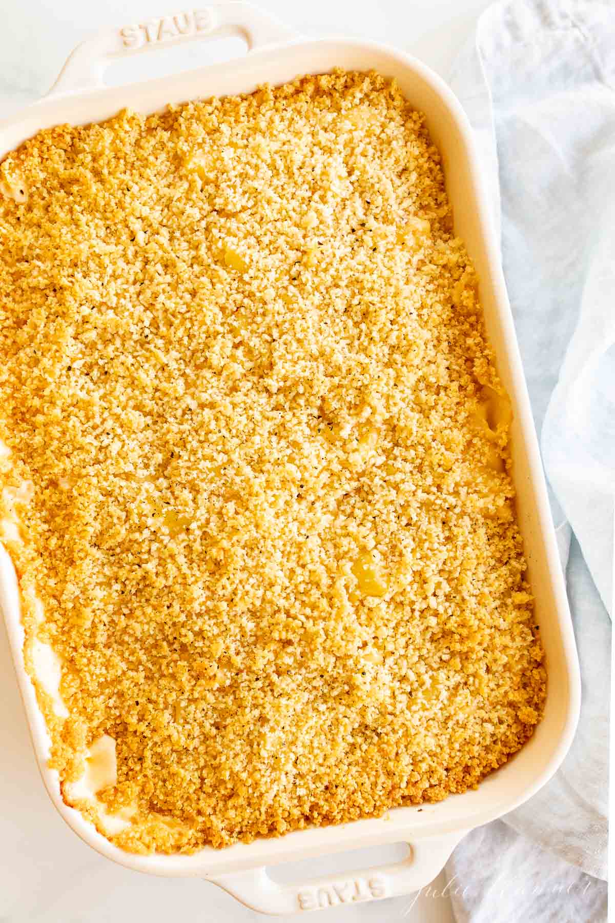 bacon mac and cheese in a white baking dish topped with bread crumbs.