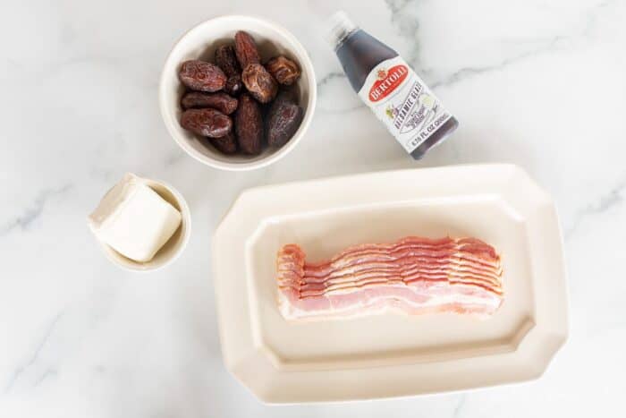 A marble surface with ingredients for bacon wrapped dates.