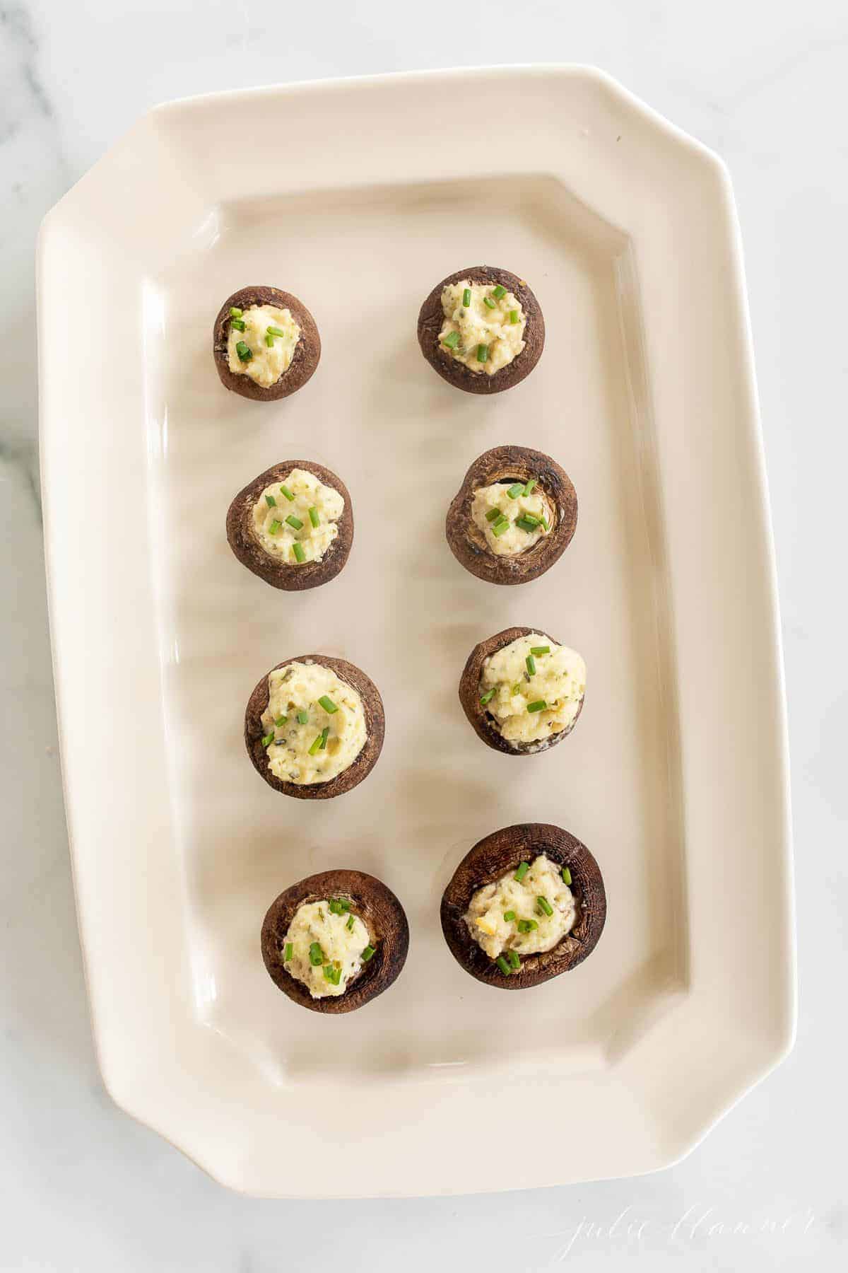 A white tray full of Boursin stuffed mushrooms.