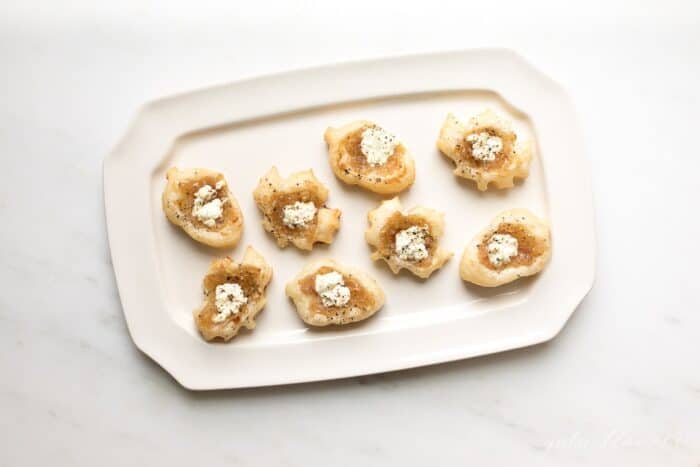 A rectangular white tray with onion tart hors d'oeuvres.