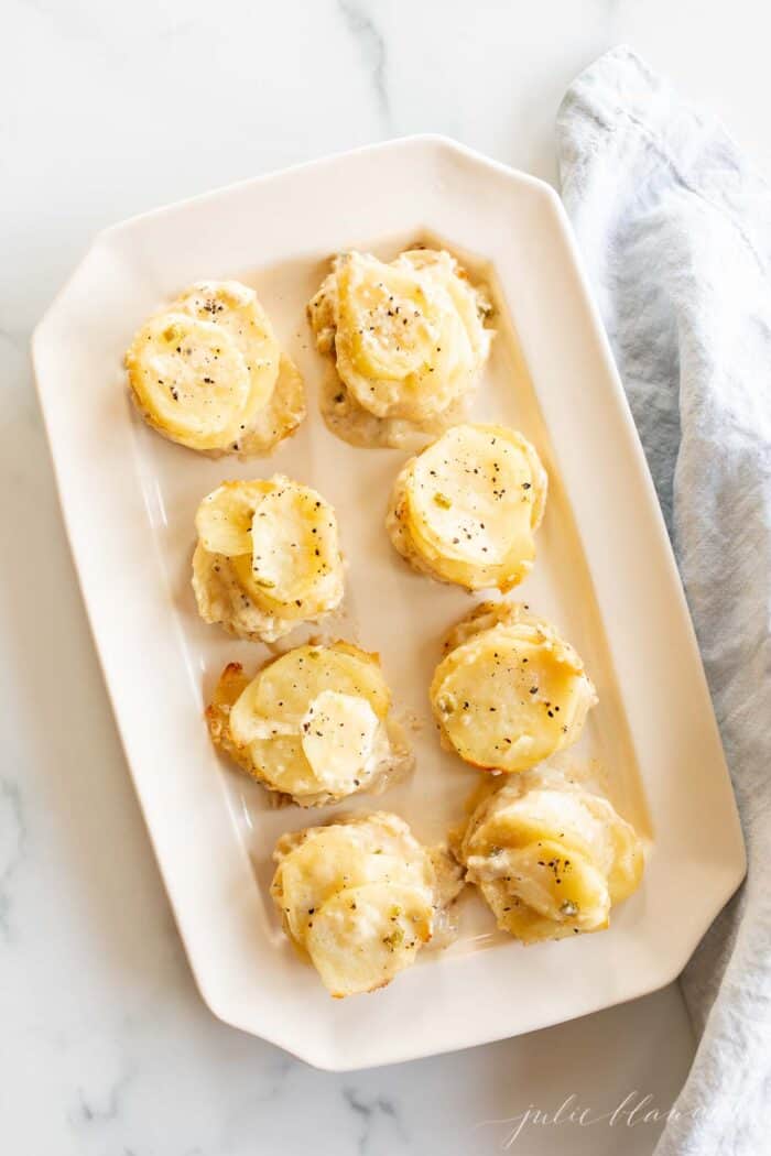 Potato gratin stacks in a gold muffin pan for individual servings.