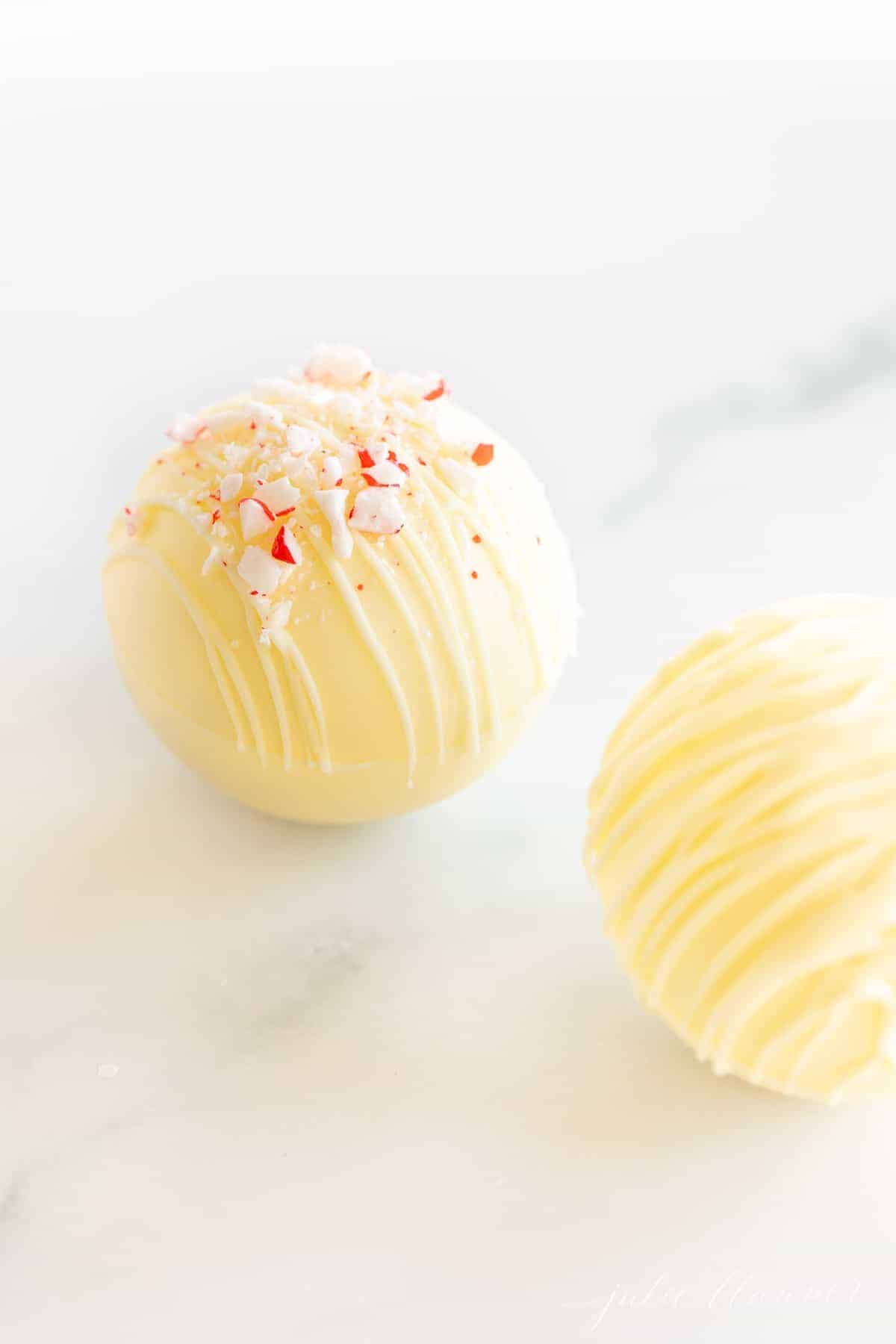 White hot chocolate bombs on a marble surface.