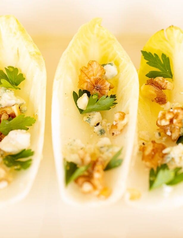 Individual endive lettuce appetizers on a white platter.