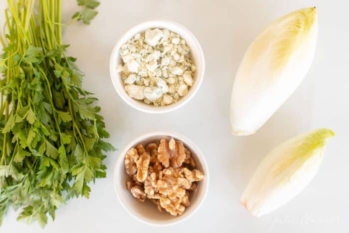 A white surface with endive lettuce and ingredients for an endive appetizer.