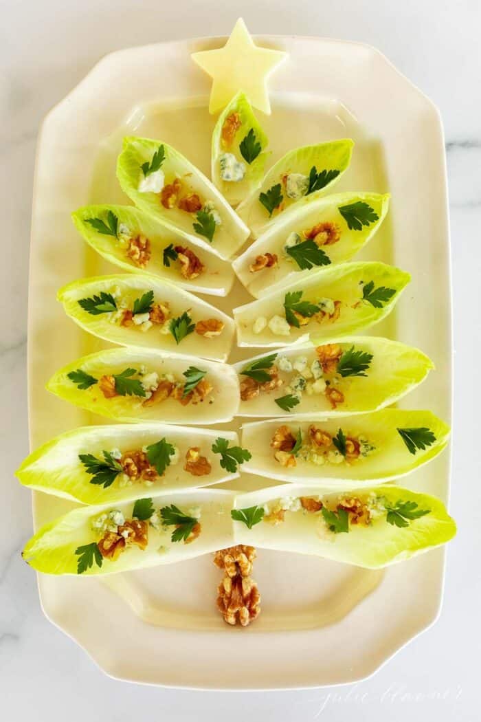 Endive lettuce salad on a white platter formed into a Christmas tree for a holiday hors d'oeuvre.