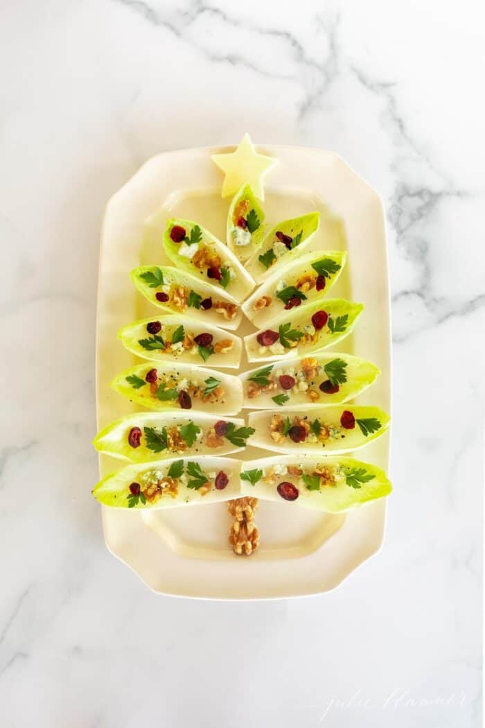 Endive salad on a white platter formed into a Christmas tree for a holiday hors d'oeuvre.