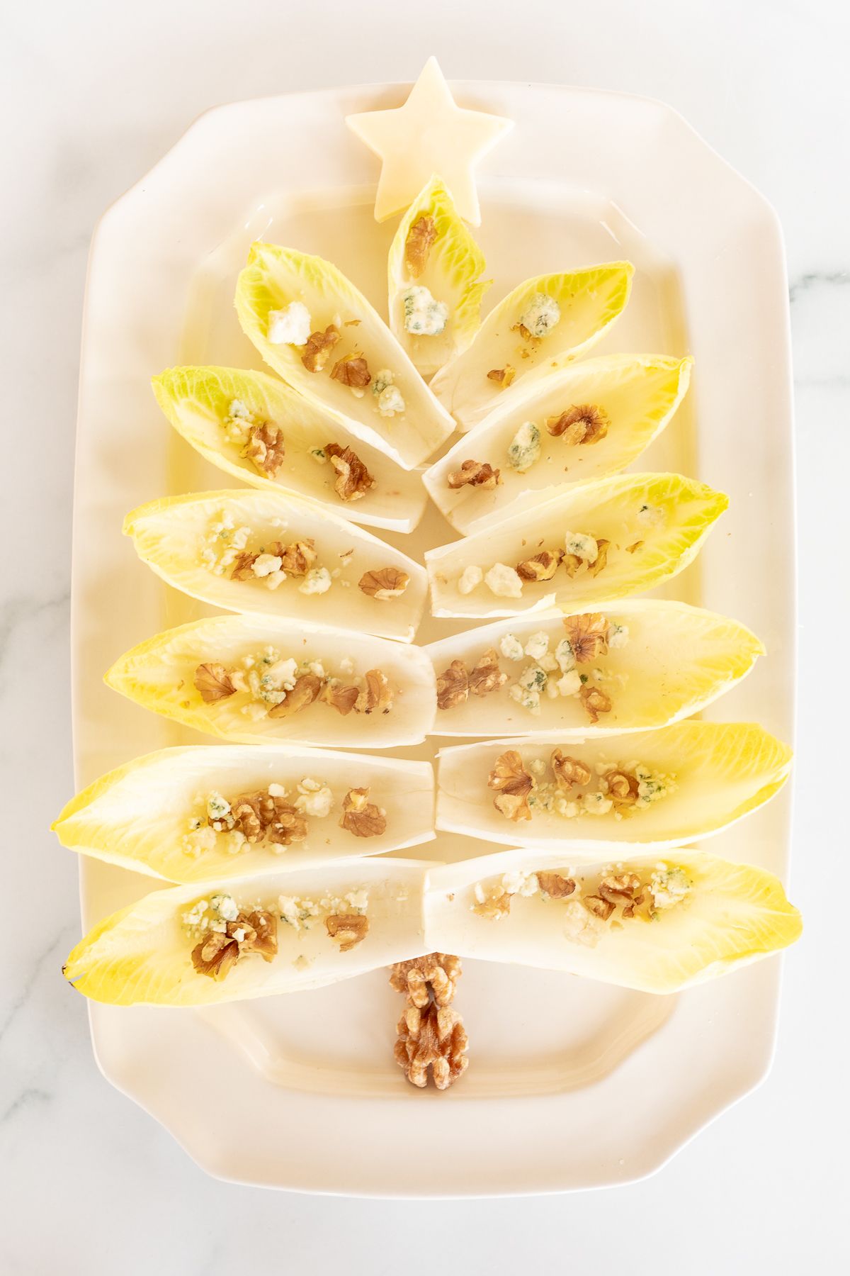 An endive salad laid out as a Christmas tree on a white platter.
