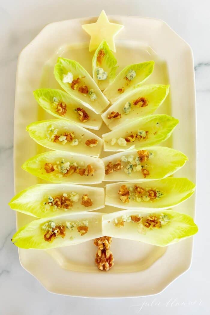 Endive lettuce leaves on a white platter formed into a Christmas tree for a holiday hors d'oeuvre.