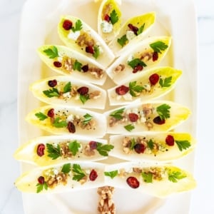 An endive salad laid out as a Christmas tree on a white platter.