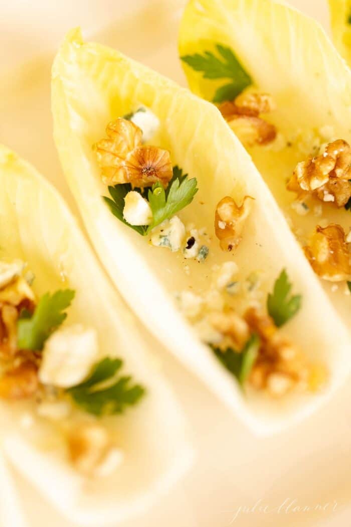 Individual endive appetizers on a white platter.
