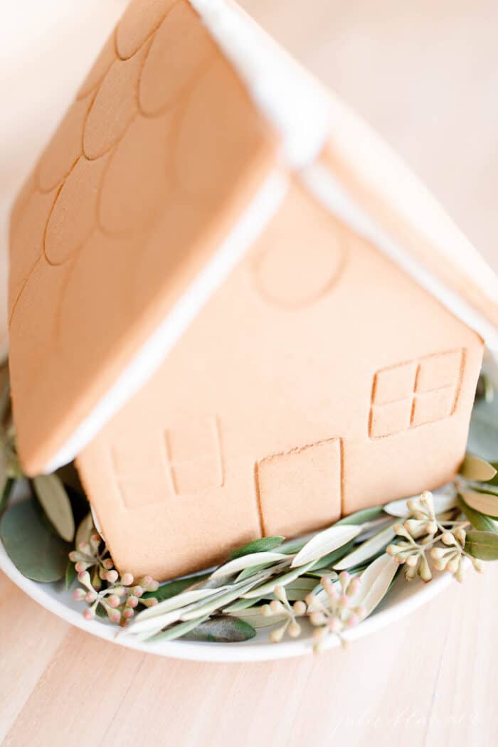 A gingerbread house with fresh greenery surrounding for nordic christmas inspiration