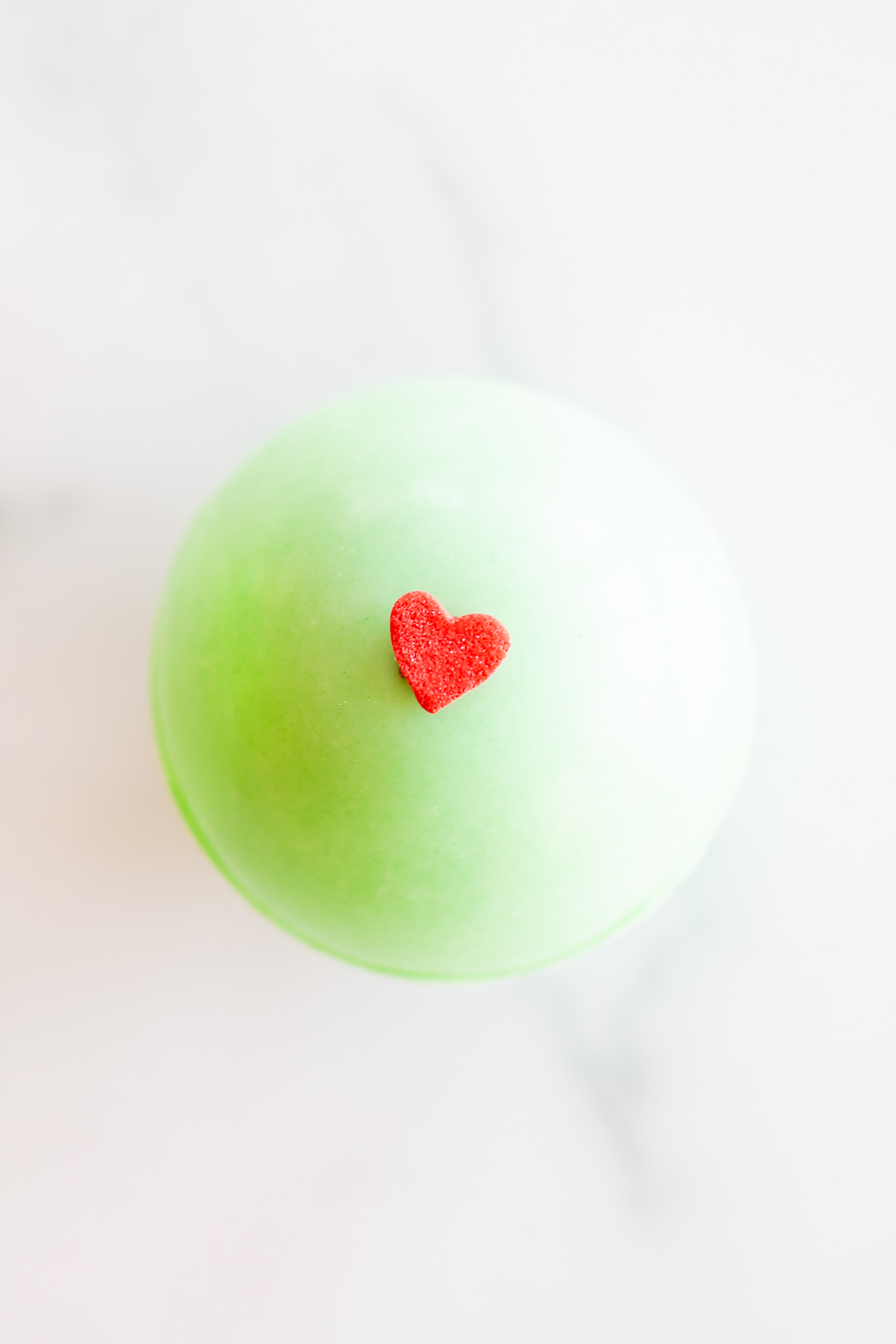 A grinch hot chocolate bomb with a red heart on it