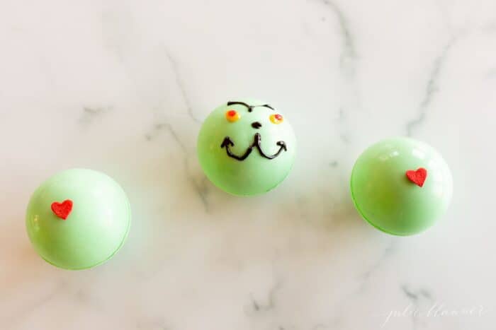 A marble surface with green grinch hot chocolate bombs.