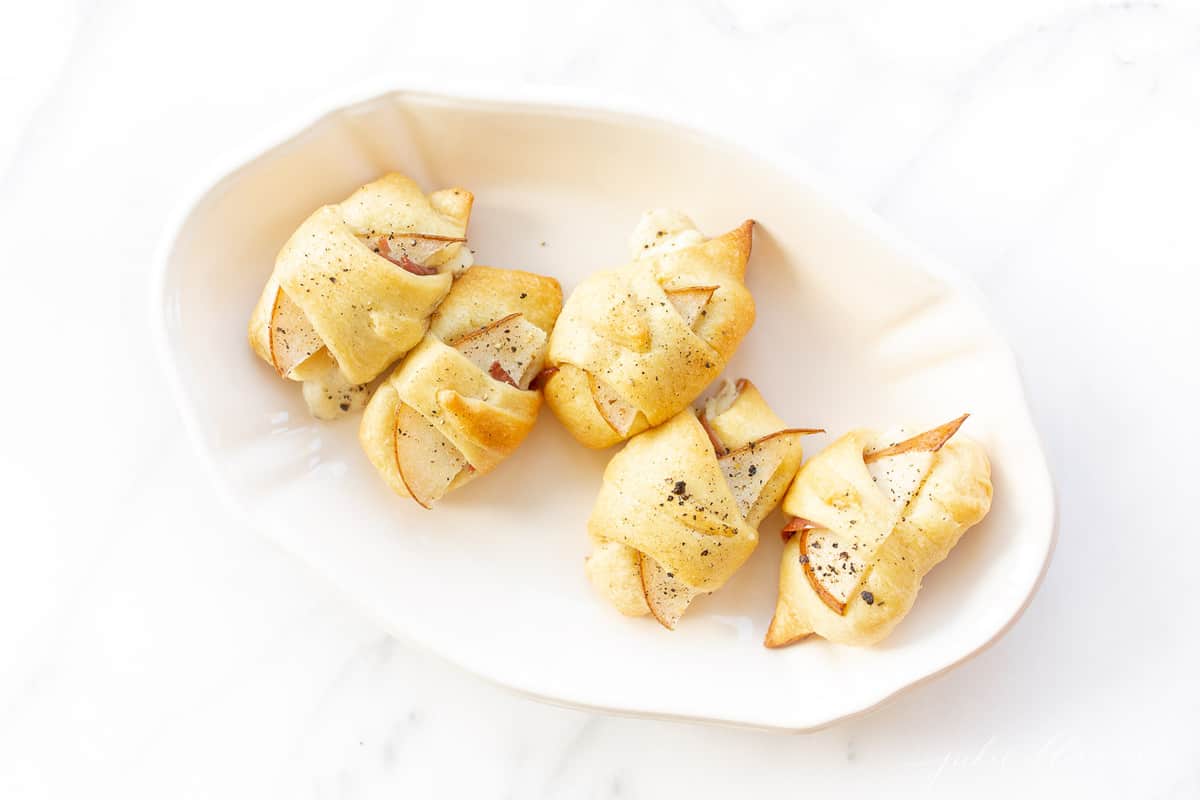 A white tray with a baked pear hors d'oeuvre