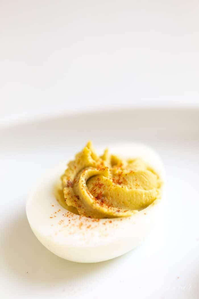 A single deviled egg hors d'oeuvre on a white plate.
