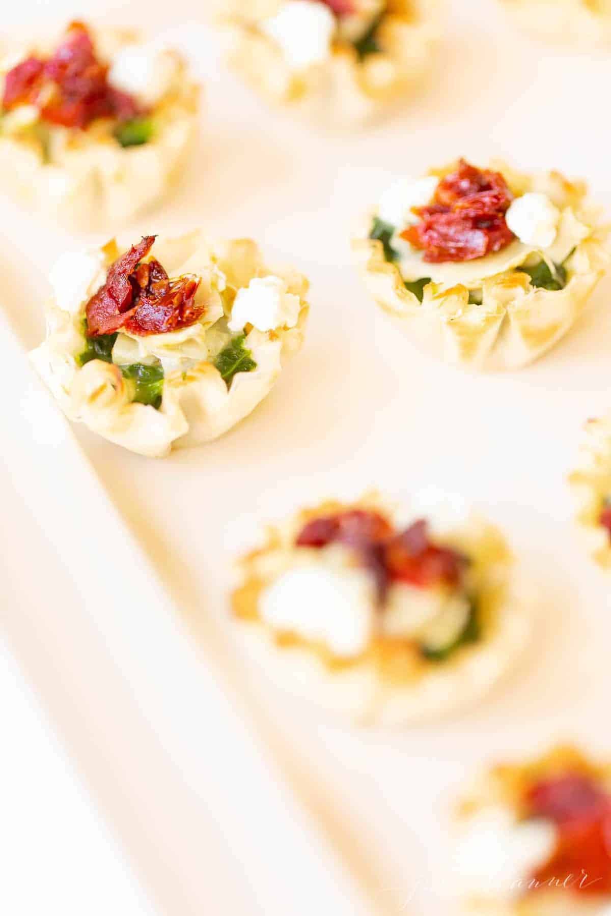 A white tray filled with individual spinach dip hors d'oeuvres.