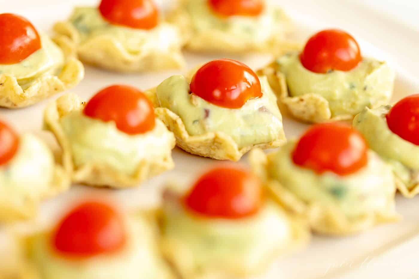 Tortilla chips filled with guacamole and topped with cherry tomatoes.