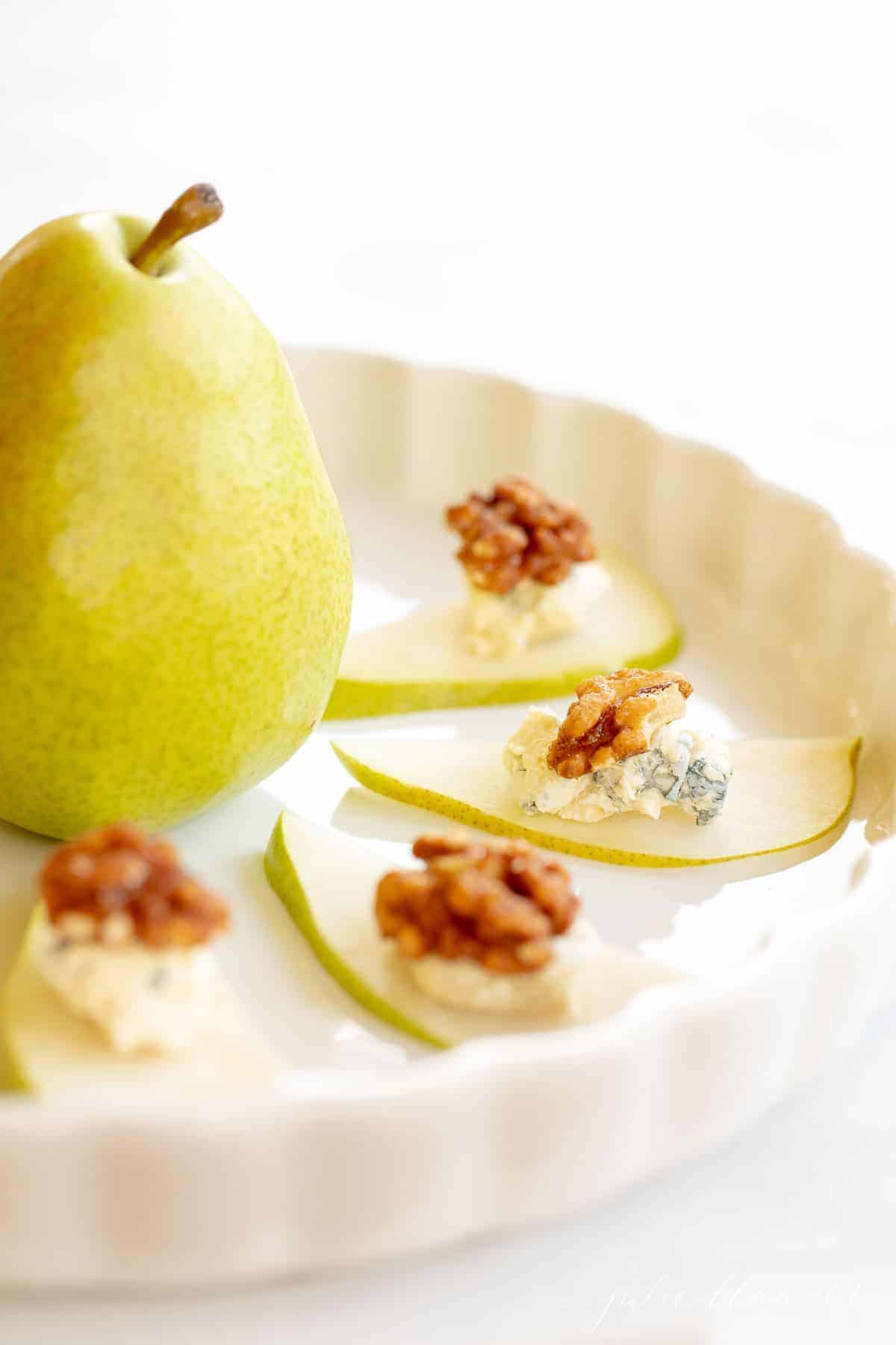 A round white tray filled with a pear and blue cheese hors d'oeuvre