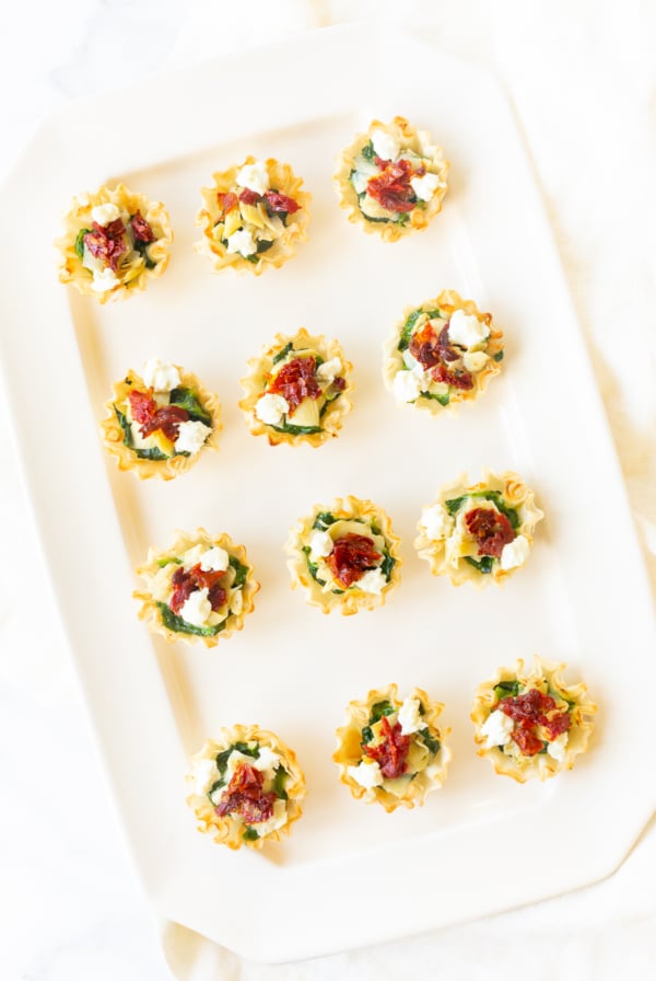Spinach and artichoke cups on a white platter in an hors d'oeuvres recipe collection