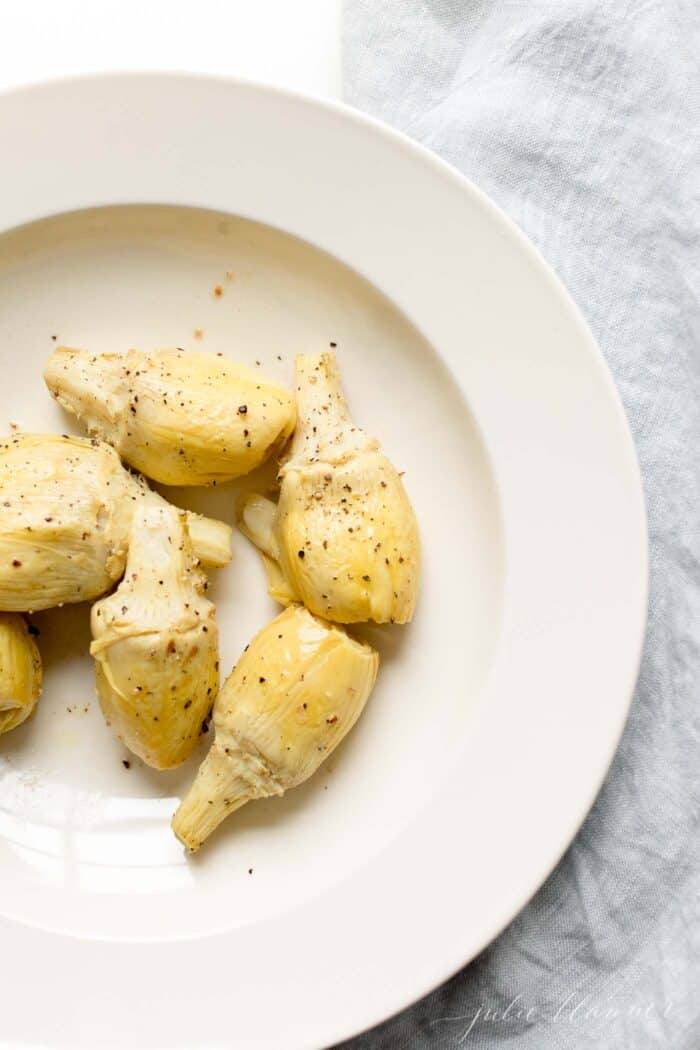 A white plate full of baked artichoke hors d'oeuvres