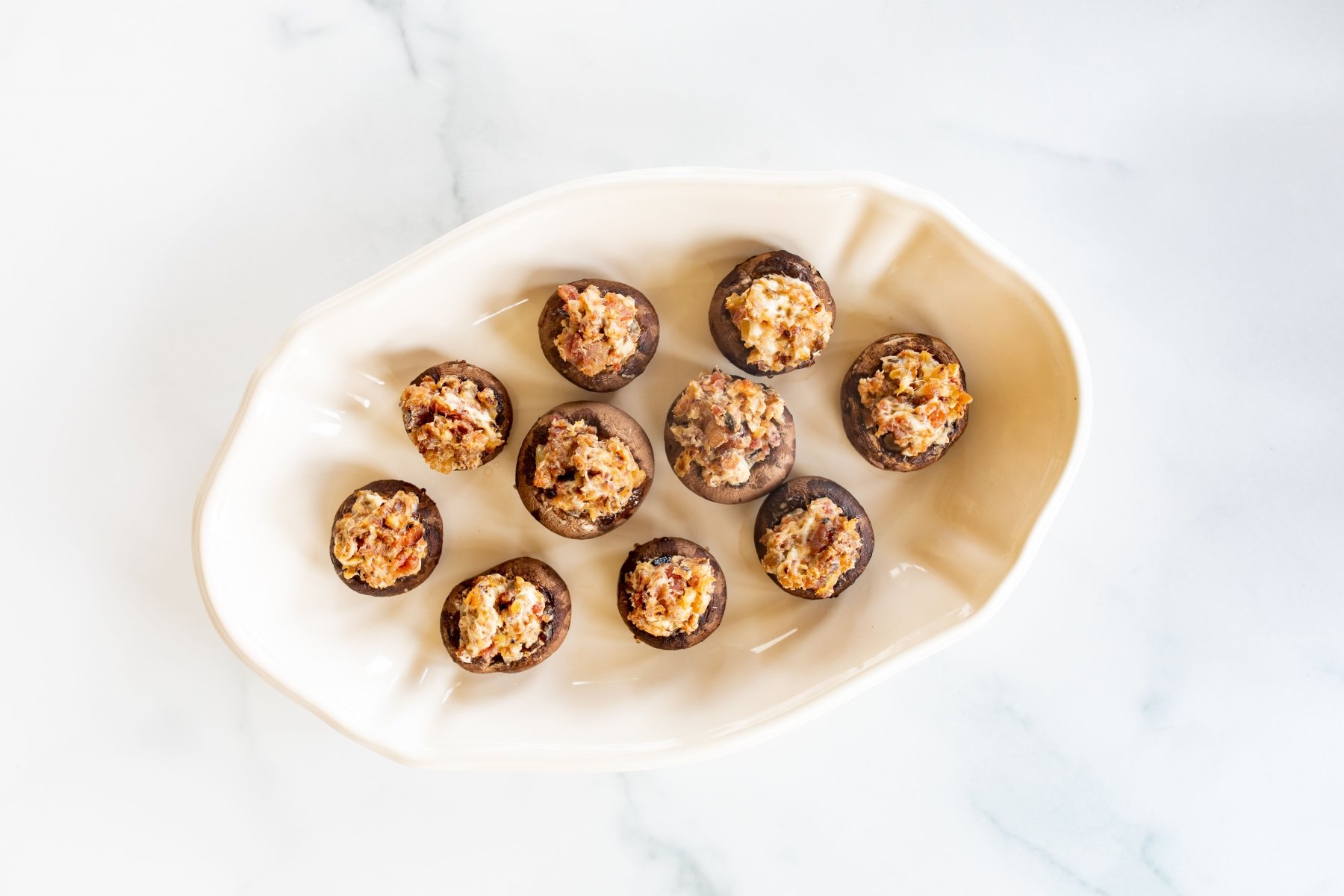 An oval white platter filled with bacon stuffed mushrooms