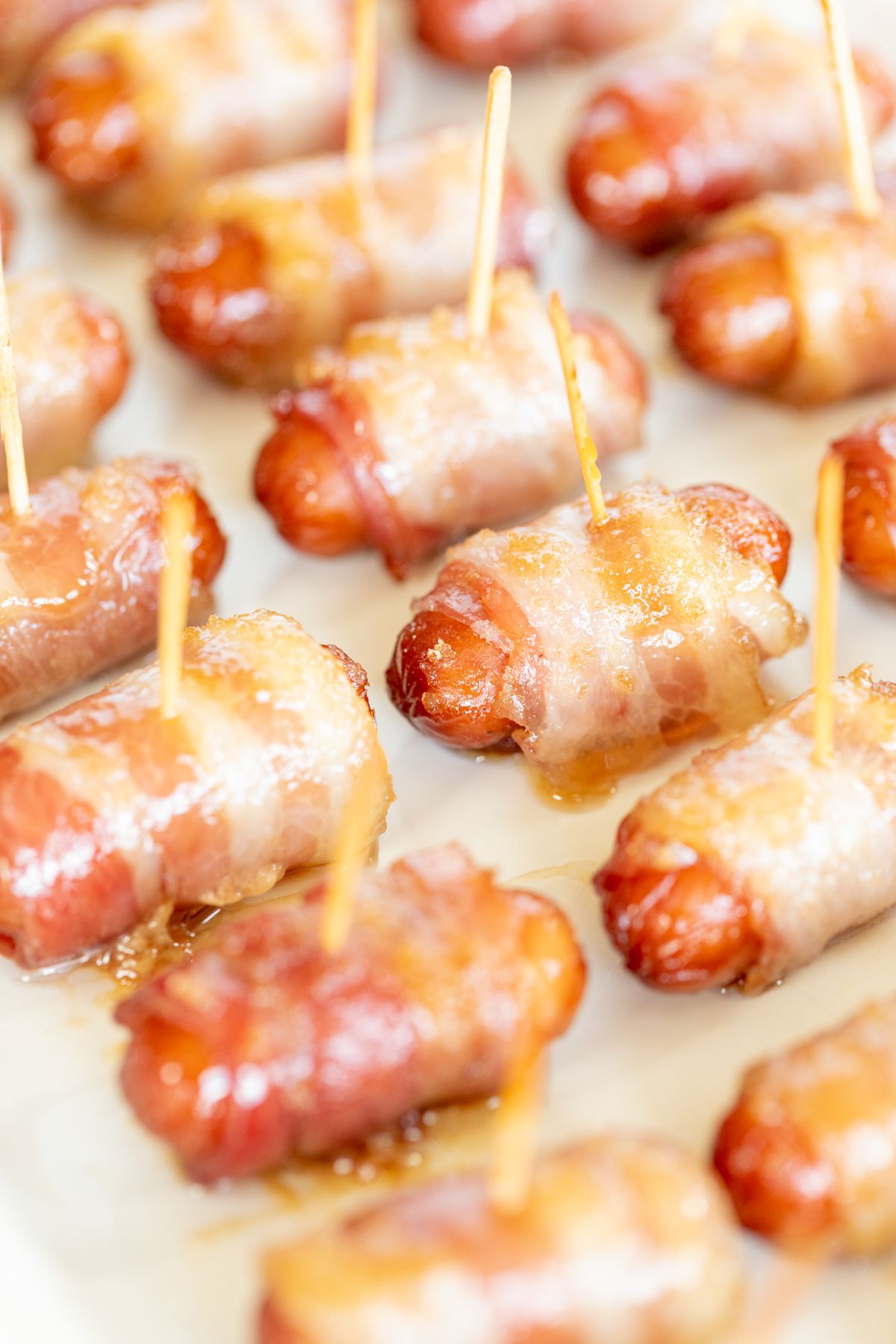 A white tray with bacon wrapped little smokies, each with a toothpick.
