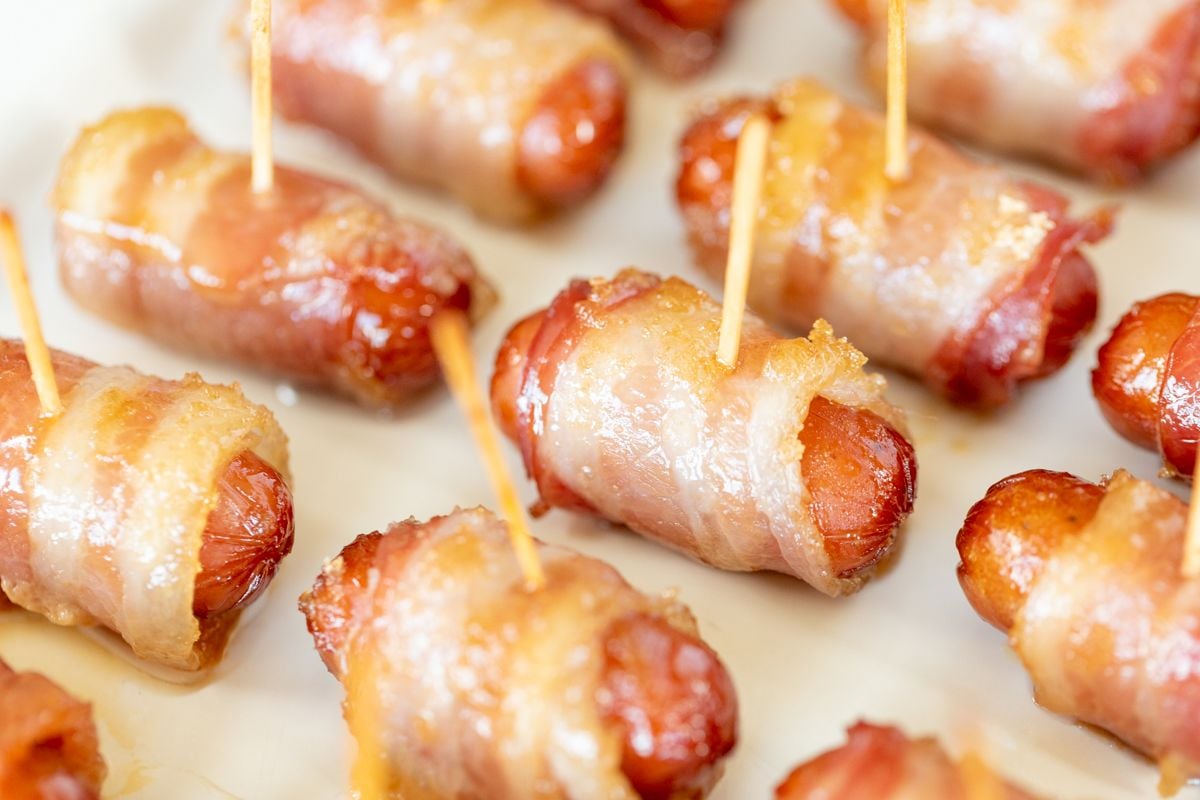A white tray with bacon wrapped little smokies, each with a toothpick.