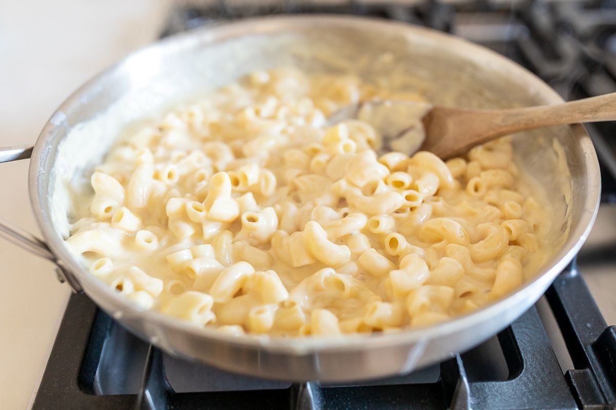 Creamy homemade mac and cheese in a silver pan on a stovetop.