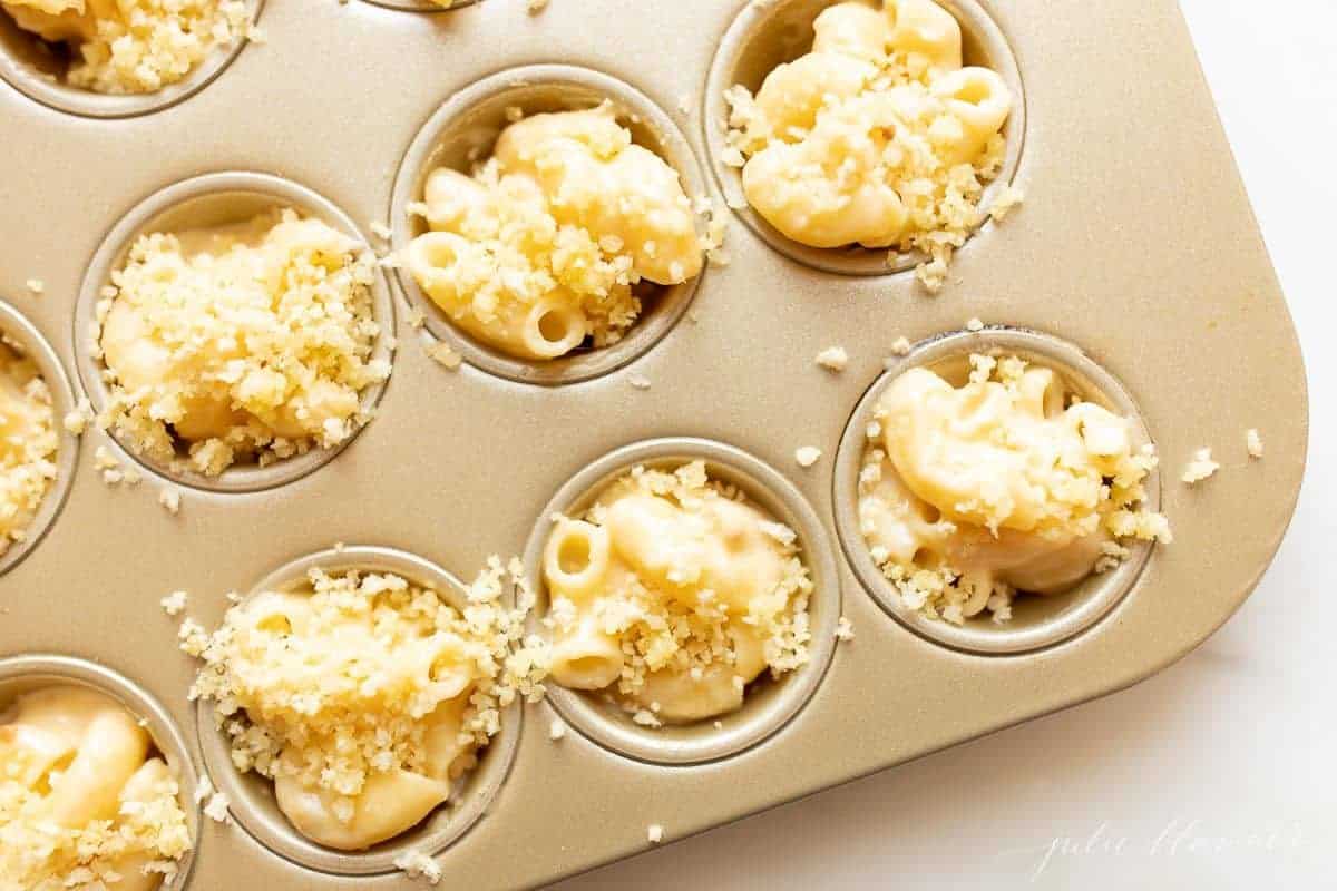 A gold mini muffin pan filled with homemade mac and cheese cups.