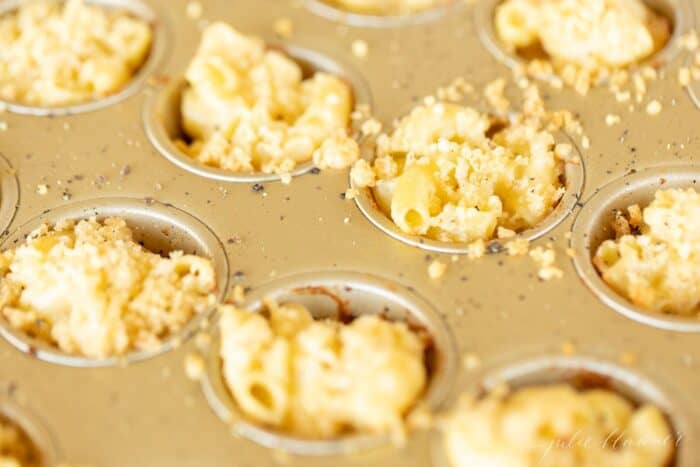 A gold mini muffin pan filled with homemade mac and cheese cups.