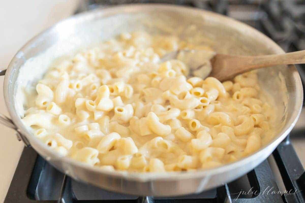 A silver pan on the stove filled with homemade mac and cheese.