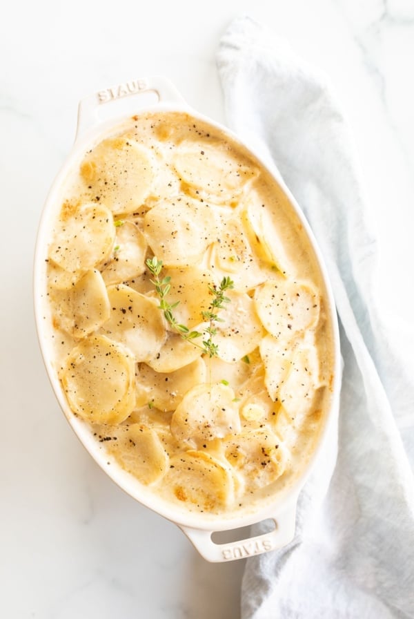 Gratin Dauphinoise potatoes in a white oval baking dish.