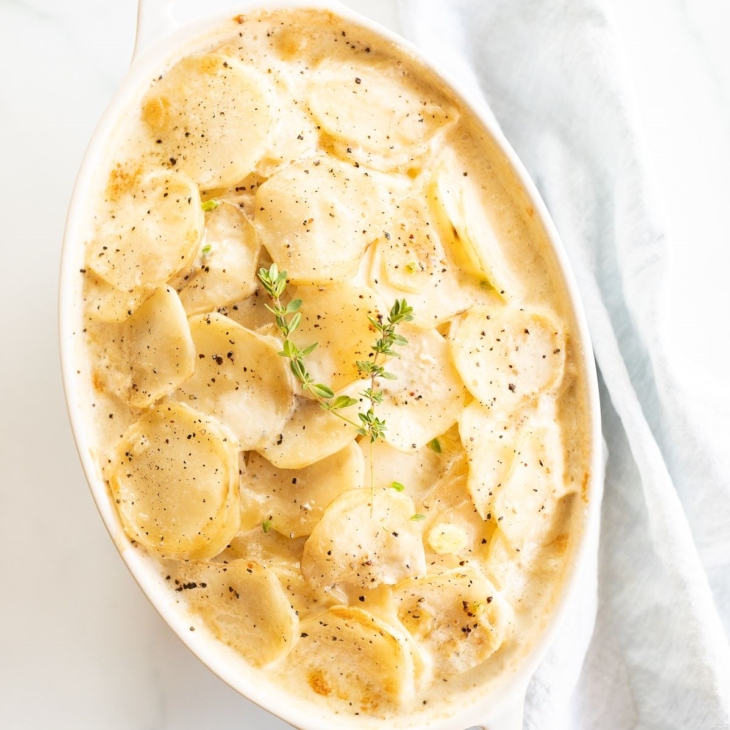 Gratin Dauphinoise potatoes in a white oval baking dish.