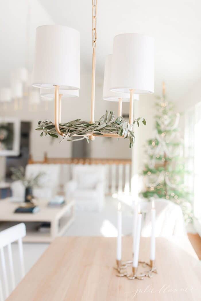 Fresh olive branches inside a brass chandelier in a Scandinavian Christmas decorated living room.