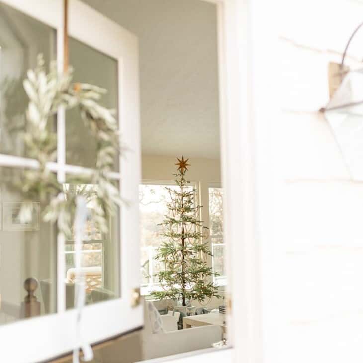 A white front porch with a natural christmas decor wreath on the dutch door.