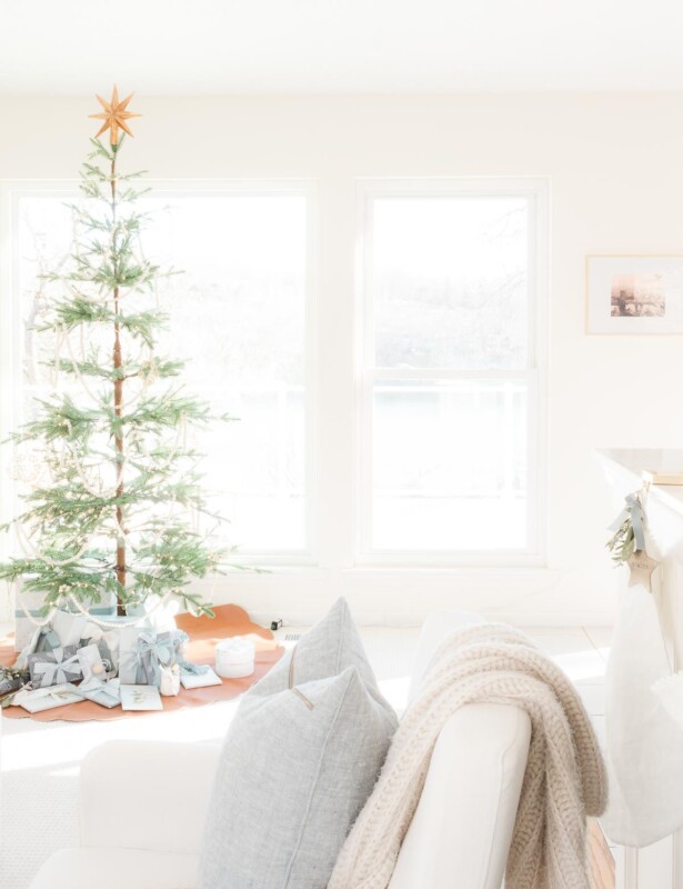 A white living room dressed for a Scandinavian Christmas with a simple Scandinavian tree.