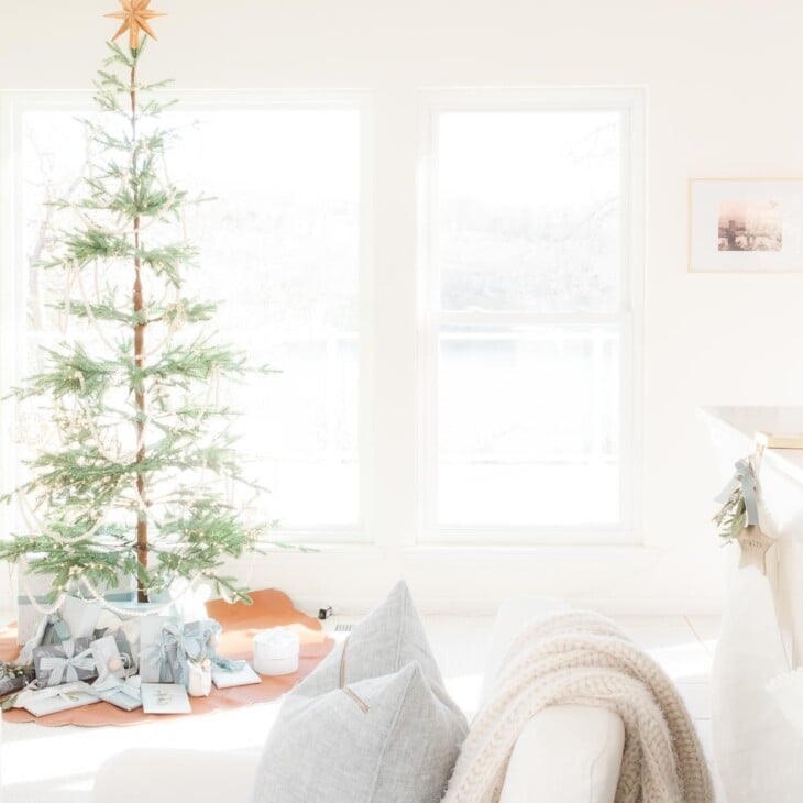 A white living room dressed for a Scandinavian Christmas with a simple Scandinavian tree.