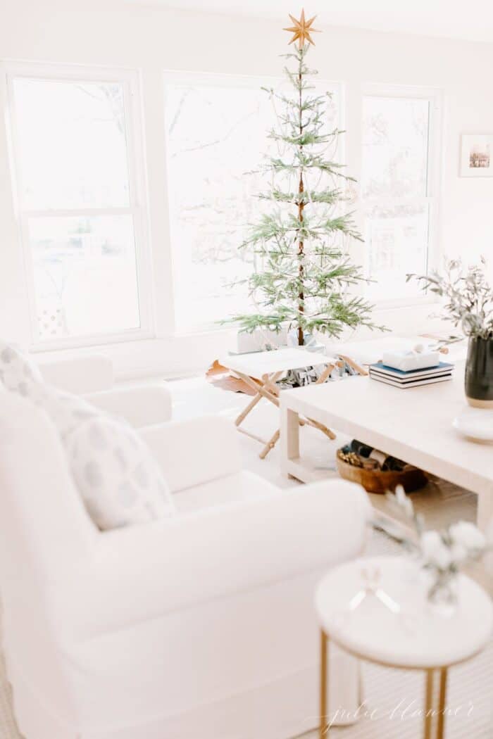 A white living room dressed for a Scandinavian Christmas with a simple Scandinavian tree.