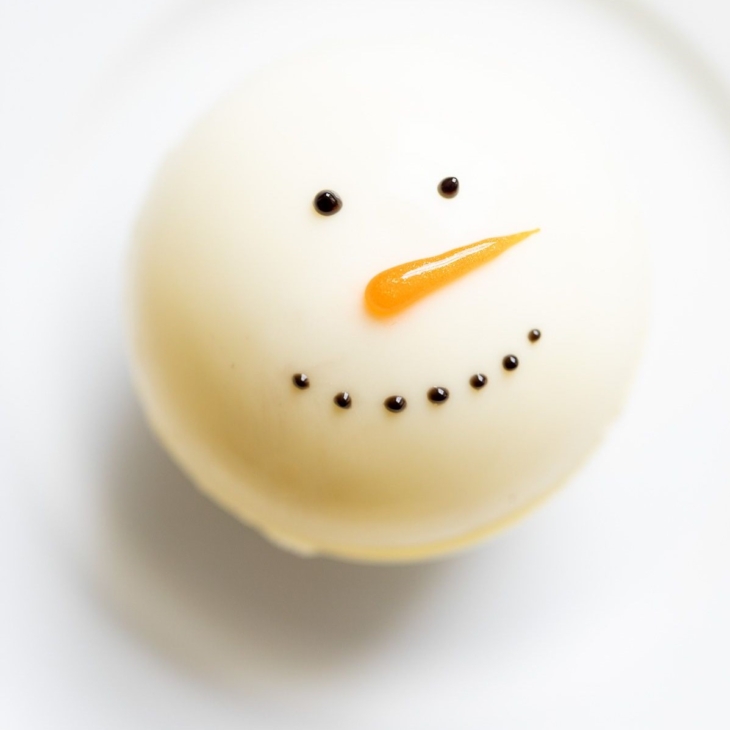 A snowman hot chocolate bomb on a white plate.