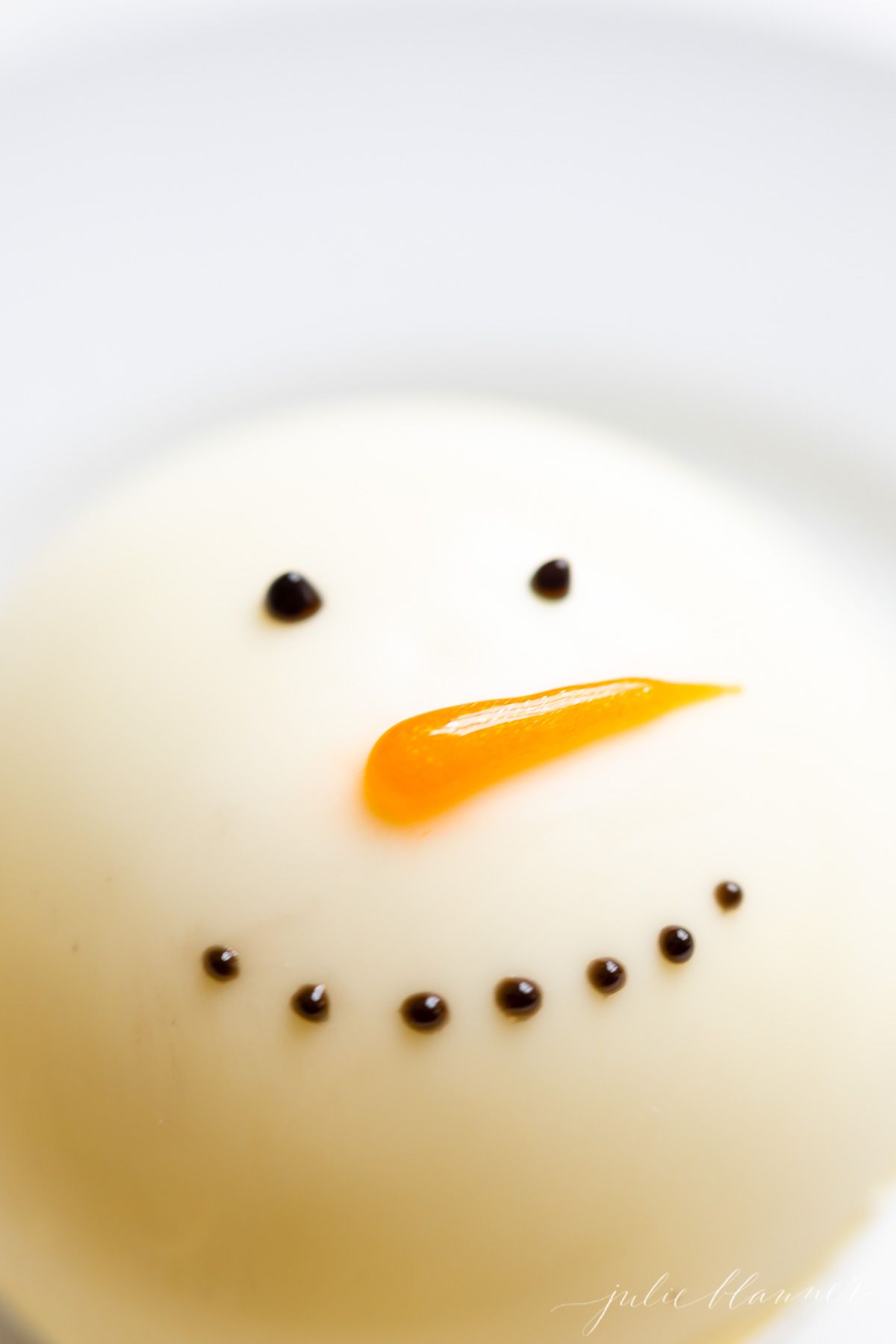 Close up of a white chocolate snowman hot chocolate bomb.
