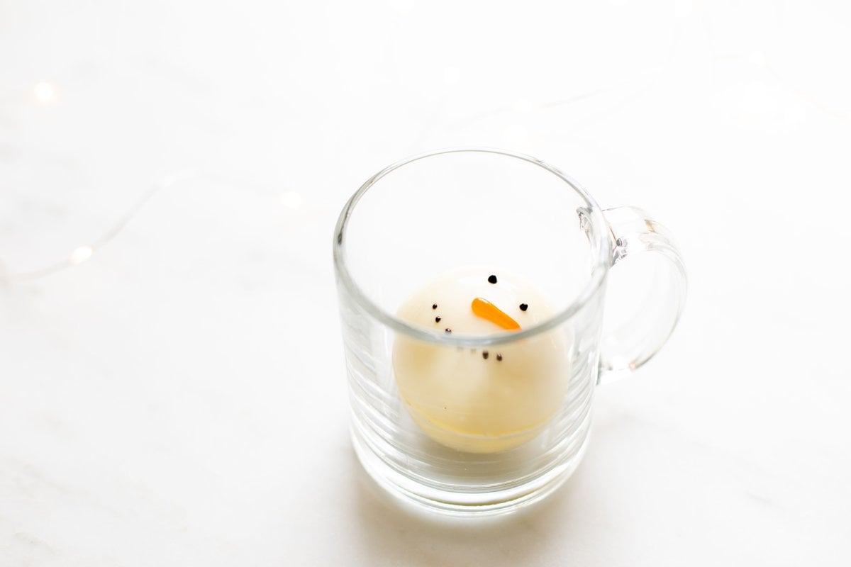 A clear glass mug with a snowman hot chocolate mug inside.