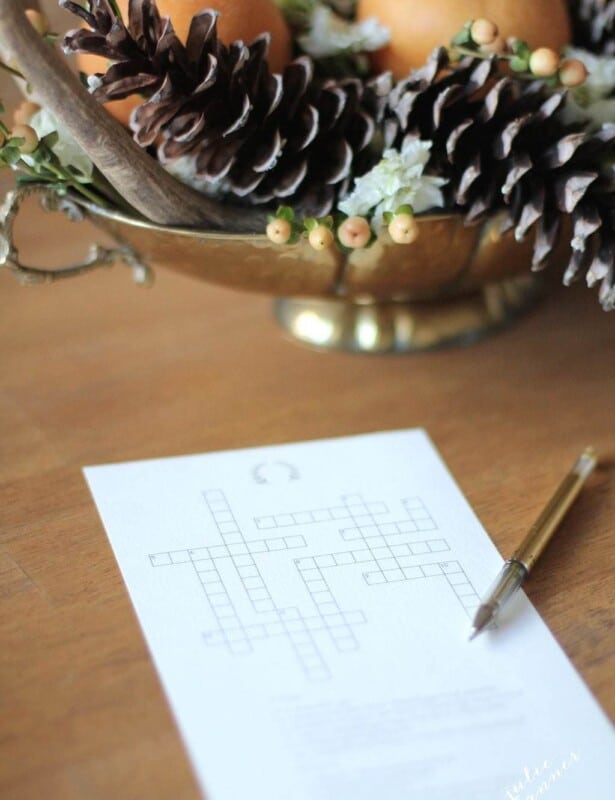 A printable Thanksgiving crossword puzzle on a wooden table with a gold centerpiece in the background.