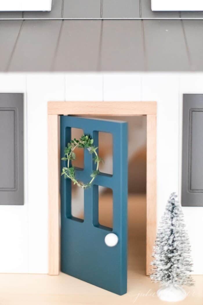 A child's doll house with a thyme wreath on the blue front door.