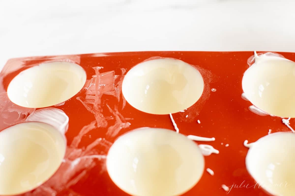 White chocolate melted into a red silicone sphere mold.