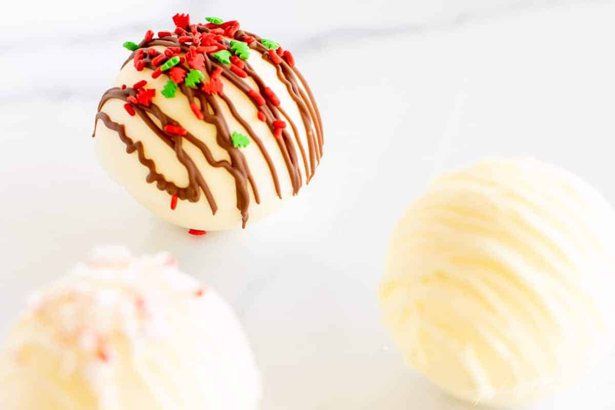 White hot chocolate bombs on a marble surface.
