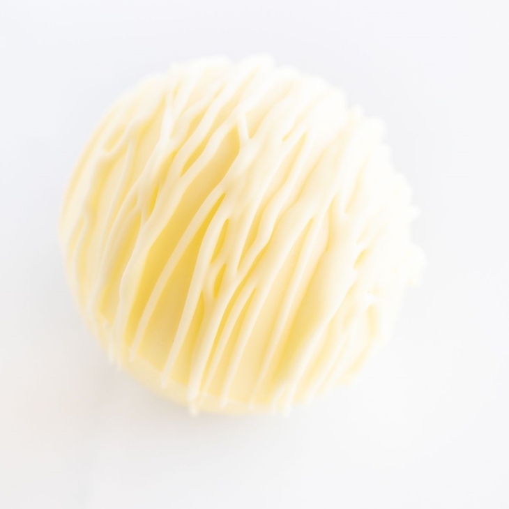 a white chocolate hot chocolate bomb on a white countertop