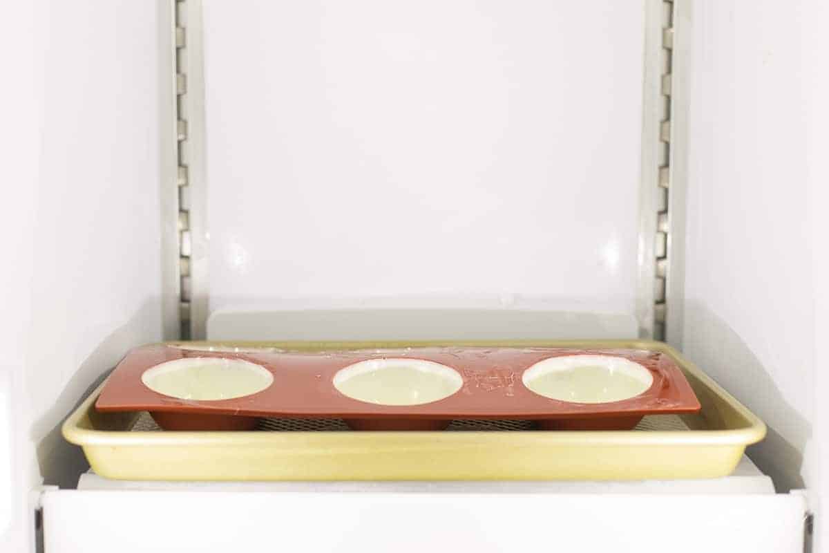 A gold baking tray with half spheres of white chocolate for hot chocolate bombs.